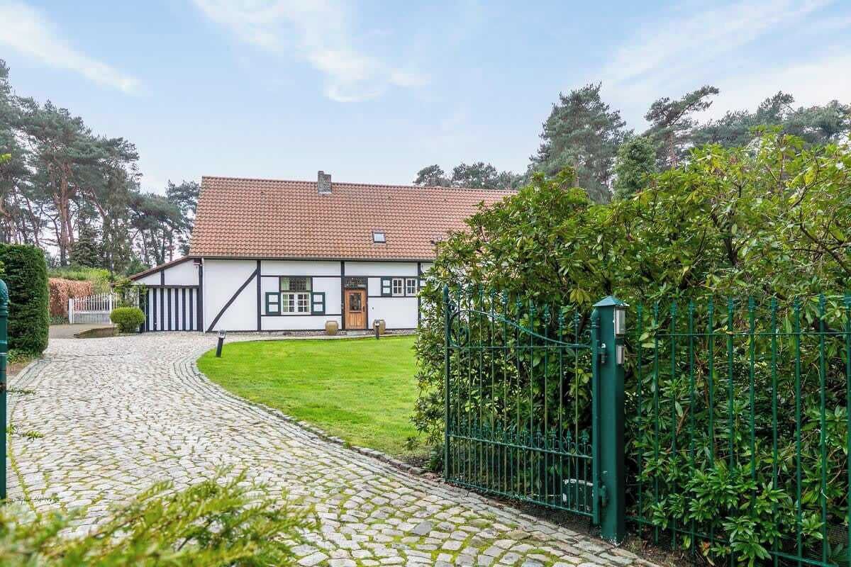A traditional house with a tiled roof, a stone pathway leading to the entrance, and a green fence.