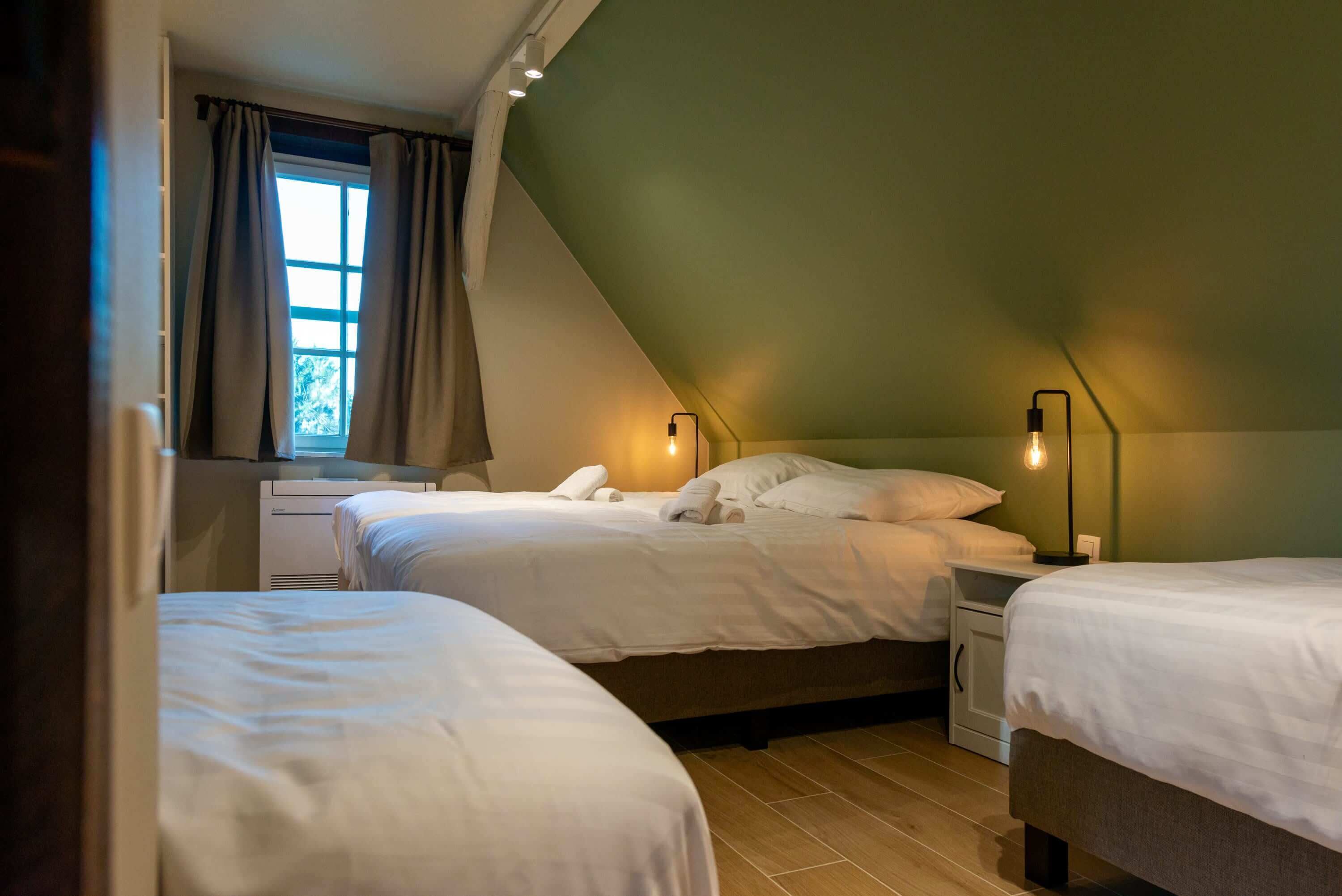 Ein Schlafzimmer mit zwei Betten, einem Fenster mit Vorhängen und Nachttischlampen.