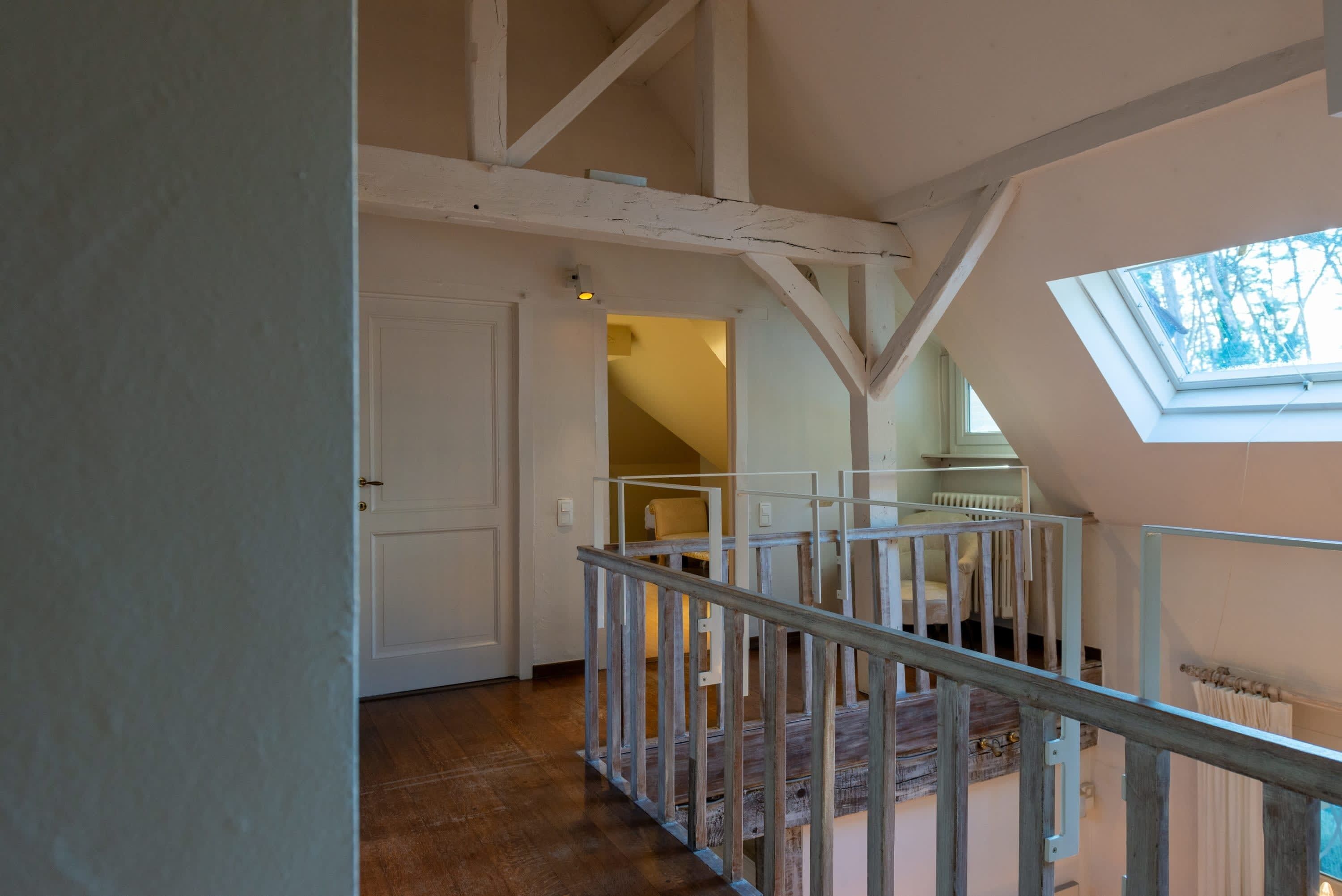 Eine Treppe mit Holzwandlaufgang führt zu einer zweiten Etage. Über der oberen Etage ist ein Oberlicht zu sehen.