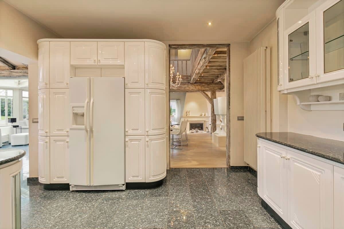 A kitchen with white cabinetry, a granite countertop, and a visible refrigerator.