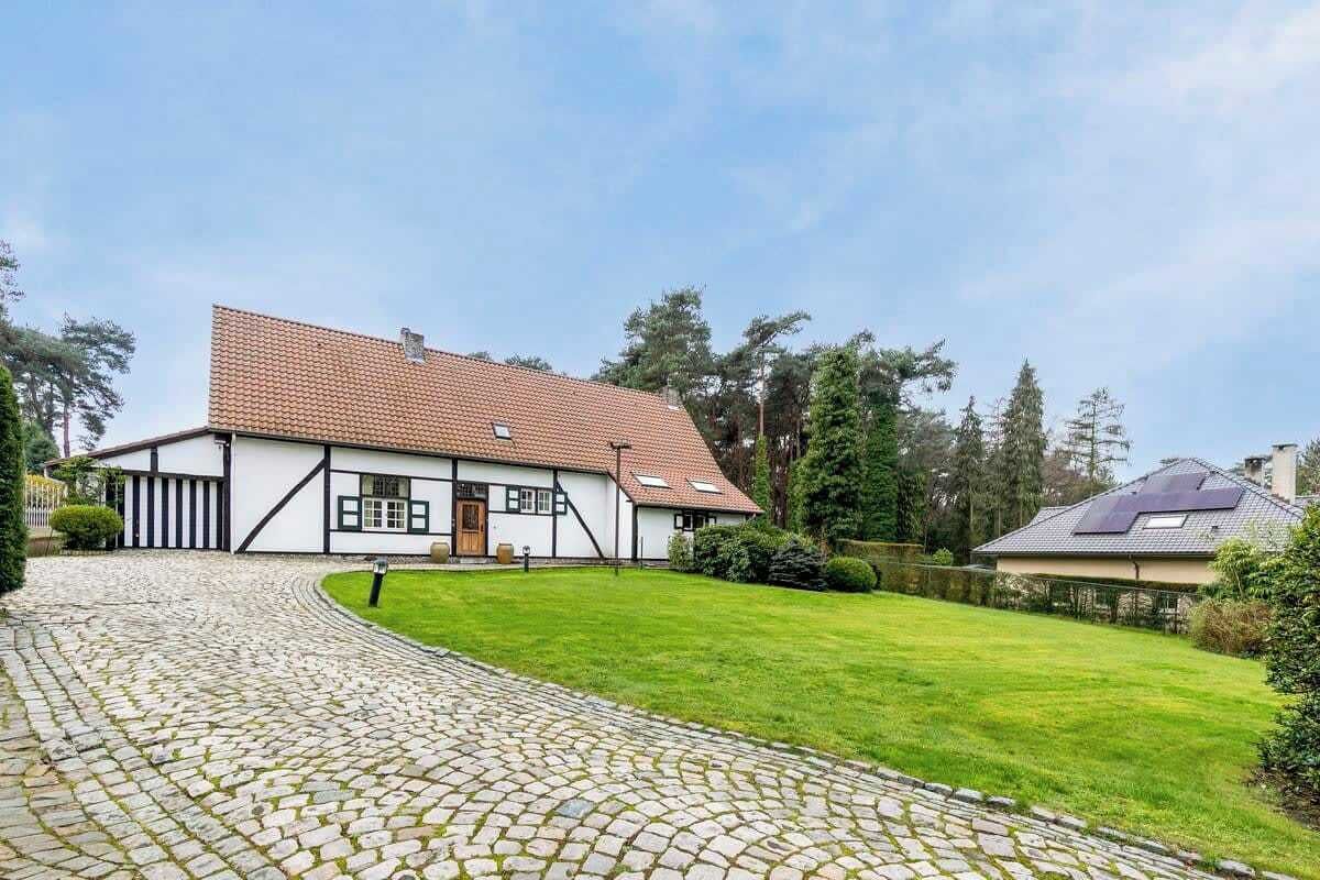 Ein traditionelles Haus mit einem Ziegeldach, einem steinernen Weg, der zum Eingang führt, und einem gepflegten Rasen.