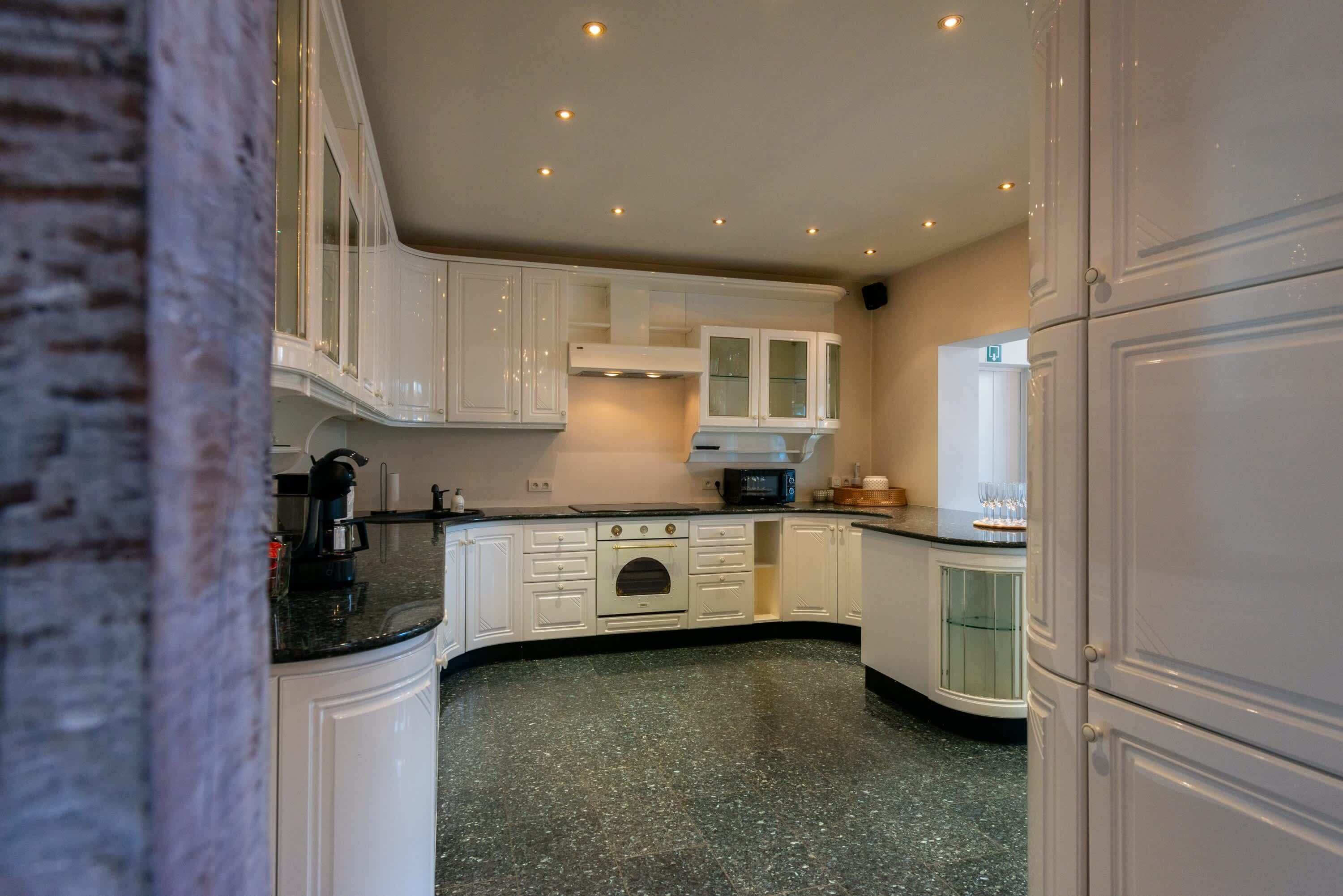 A kitchen with white cabinets, a black countertop, and a built-in oven.