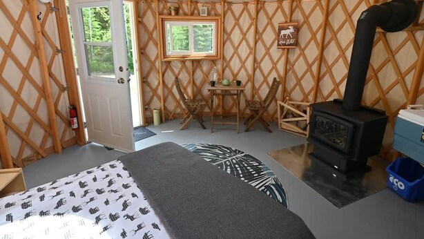 Een joert met een bed, een tafel, stoelen, een kachel en een raam.