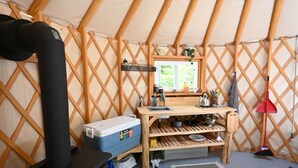 Een compact en overzichtelijk interieur met een kitchenette, een bed en een raam dat zorgt voor natuurlijk licht.