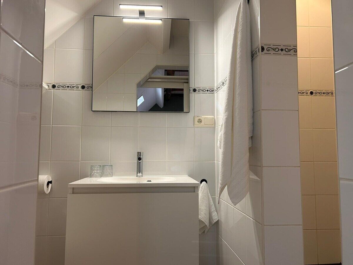 A bathroom with a white sink, a mirror, and a shower curtain.
