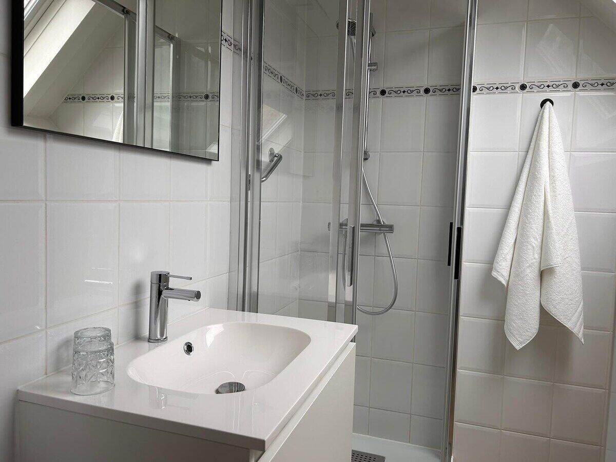 Een moderne badkamer met een douchecabine, een wit wastafelmeubel en een handdoek aan een rek.