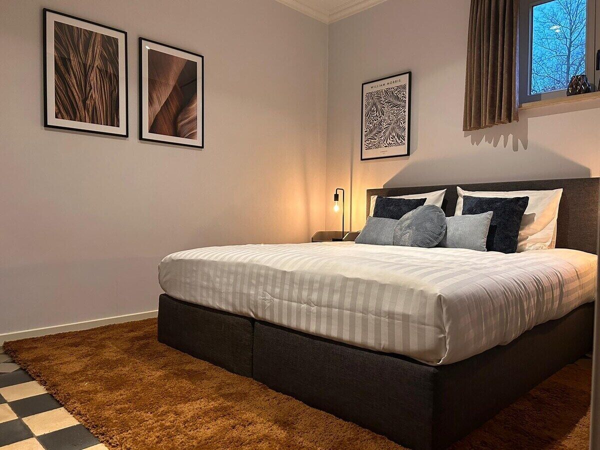 Une chambre à coucher avec un lit, un tapis et des œuvres d’art encadrées accrochées au mur.