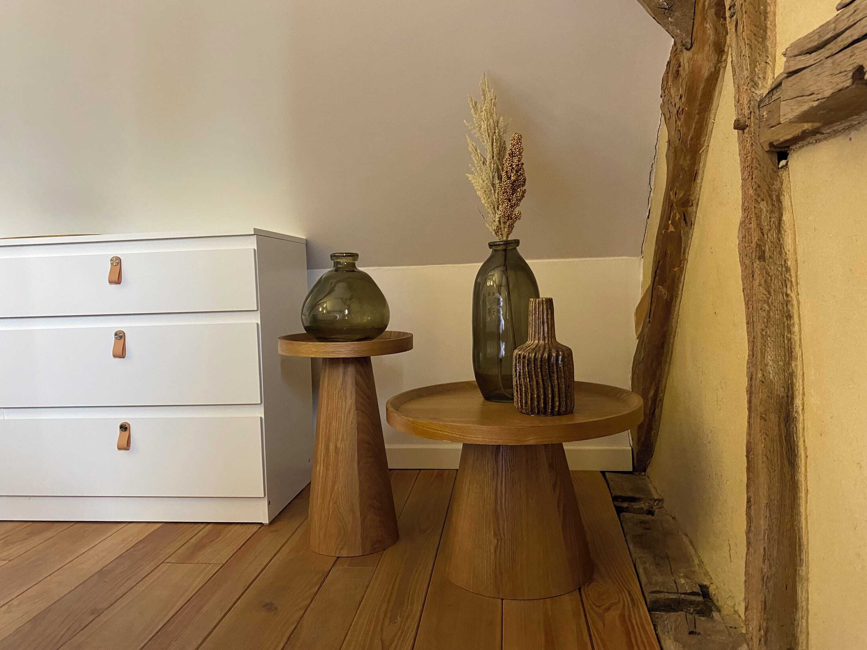 Ein Blick in ein Zimmer mit Holzboden, einem weißen Schminktisch mit braunen Griffen und zwei Holztischen mit Vasen darauf.