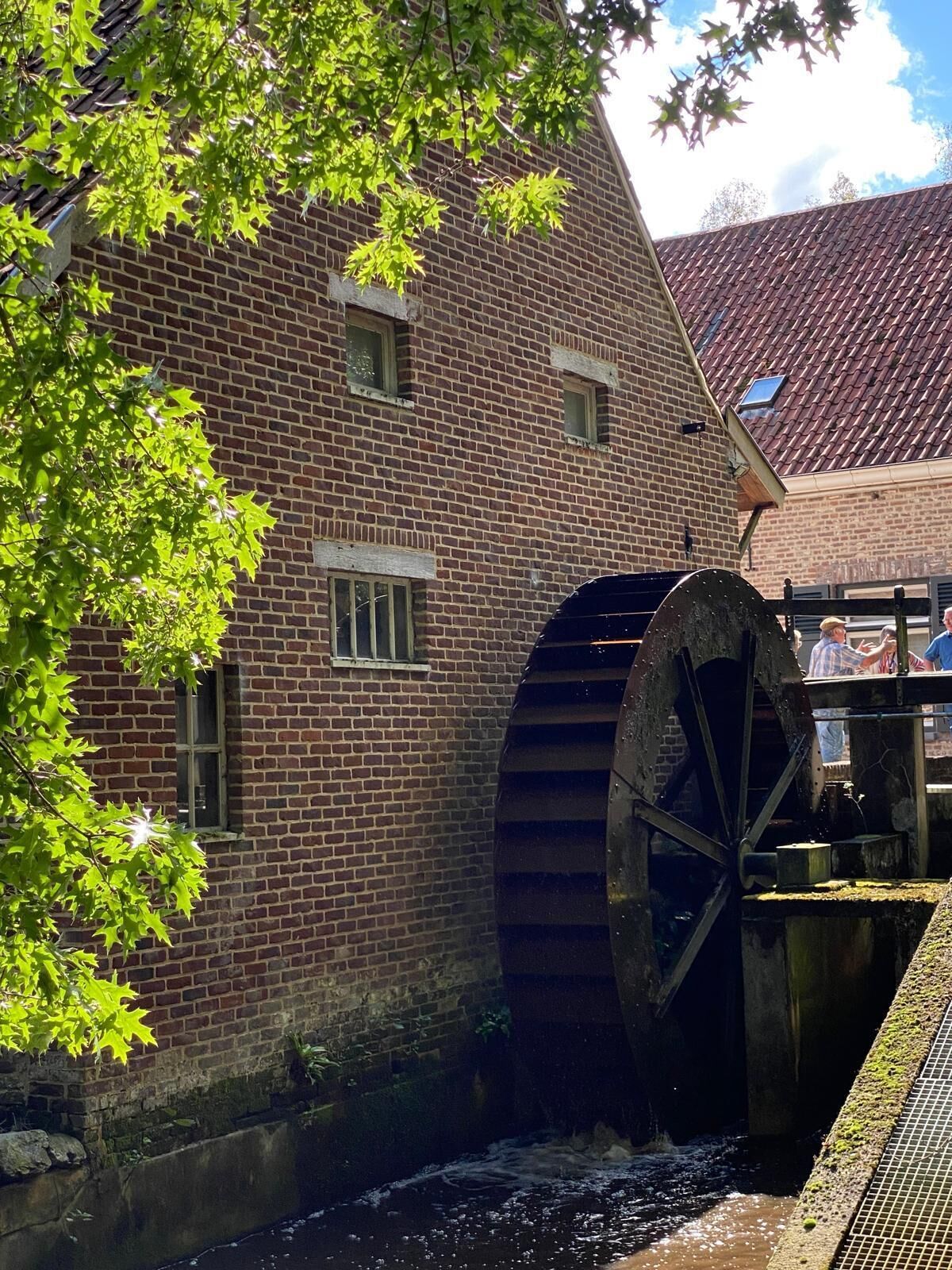 Ein Backsteinhaus mit einem großen Wasserrad und einem Kanal.