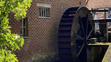 Ein Backsteinhaus mit einem großen Wasserrad und einem Kanal.