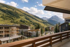 Un pueblo de montaña con edificios, un balcón de madera y vistas a las montañas.