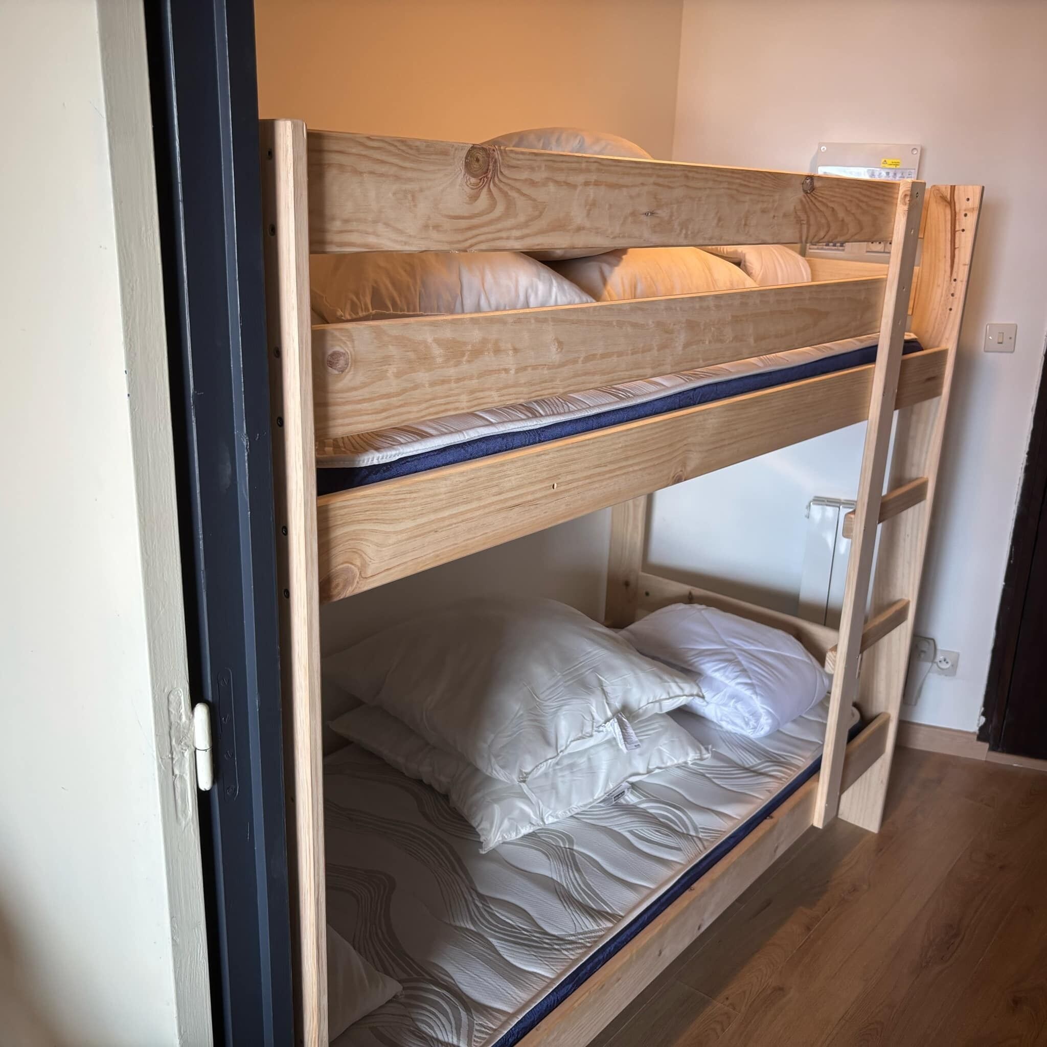 A bunk bed with two levels, each with pillows and a mattress.