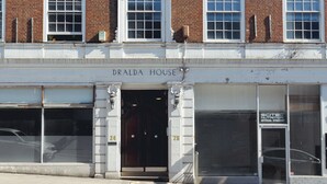 Un bâtiment à deux étages, au-dessus de l’entrée duquel on peut lire l’inscription « DRALDA HOUSE ».