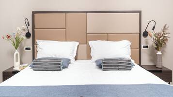 A neatly made bed with two pillows, a bedside table with a vase of flowers, and a wall-mounted charging station.