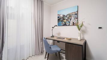 Une chambre moderne équipée d’un bureau, d’une chaise et d’un tableau représentant un paysage portuaire.