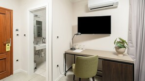 A room with a desk, chair, TV, air conditioning unit, and a bathroom visible through an open door. - Al Porto Suites (Novigrad)