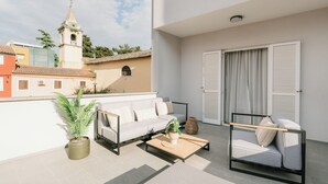 A balcony with a sofa, a coffee table, and a potted plant. - Al Porto Suites (Novigrad)