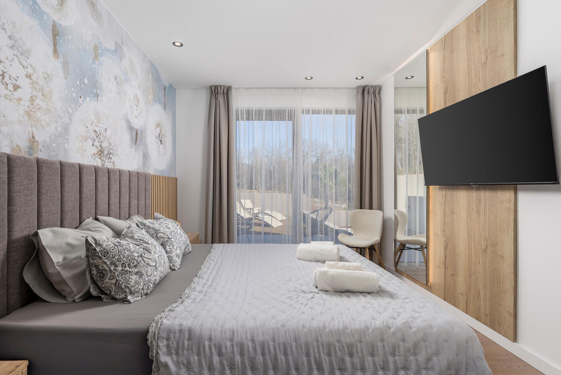 Una moderna camera d'albergo con un ampio letto, una televisione a schermo piatto montata a parete e vista all'esterno tramite ampie finestre.