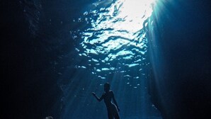 A diver in a cave with sunlight filtering through the water. - Unie  (Lyudao)