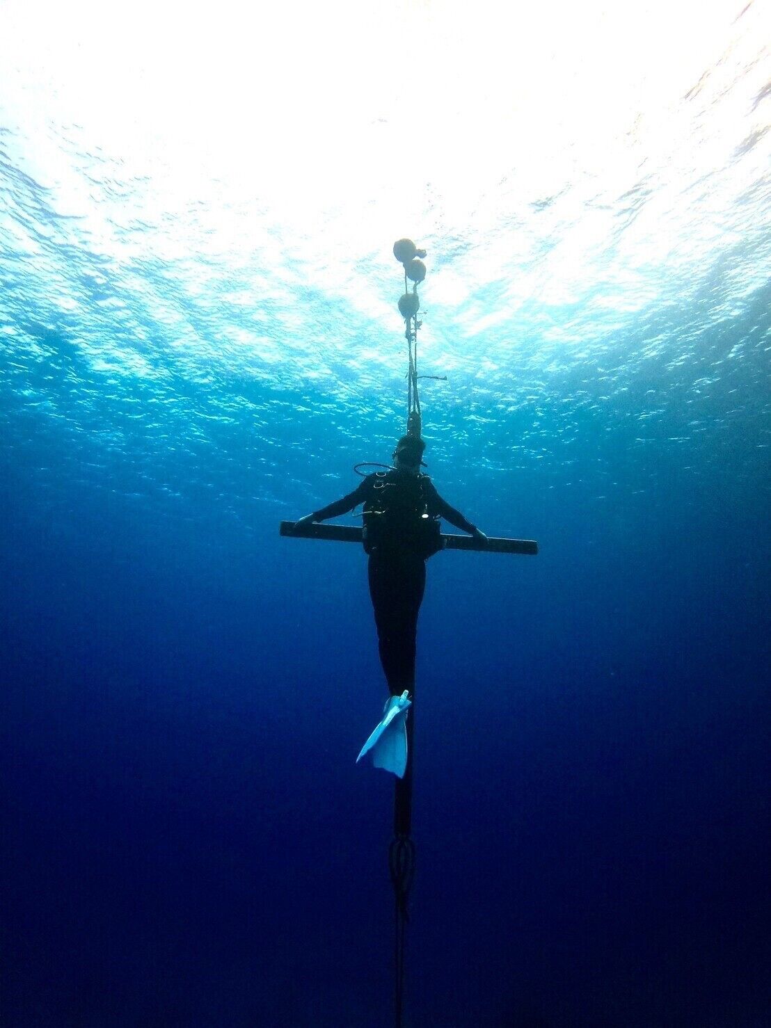 A diver descending underwater with a rope and a buoyancy control device.