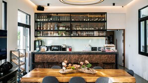 A modern bar area with shelves of liquor bottles, a wooden dining table with chairs, and a decorative centerpiece. - Unie  (Lyudao)