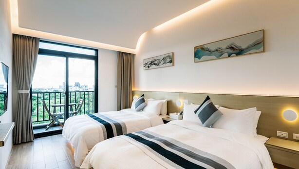 A hotel room with two beds, a balcony with a view, and artwork on the walls. - Unie  (Lyudao)