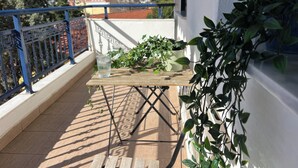Un balcon avec une table en bois, des plantes en pot et un verre d’eau.