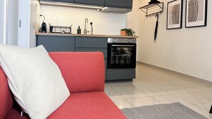 Une cuisine moderne avec des meubles gris, un four encastré et un plan de travail sur lequel on trouve une machine à café et une plante.