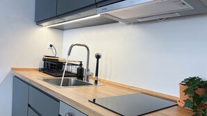 Une cuisine moderne dotée d’un plan de travail en bois, d’un évier en acier inoxydable et d’un four encastré.