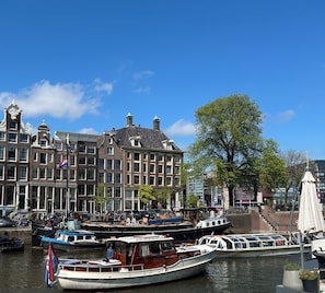 Stunning canal-side building with ornate facades and a prominent clock tower, adjacent to a modern glass structure.