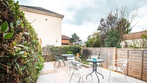 An outdoor patio area with metal chairs and tables, surrounded by a wooden fence and greenery. - Central House in Southampton (Freemantle)