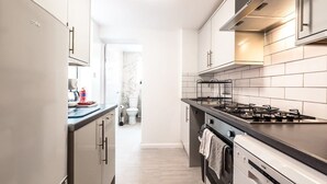 A modern kitchen with stainless steel appliances, white cabinetry, and a tiled backsplash. - Central House in Southampton (Freemantle)
