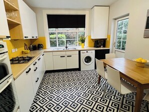 Een kleine keuken met een gasfornuis, een wasmachine en een spoelbak.
