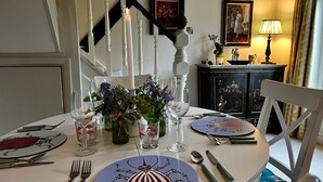 A dining table set with plates, cutlery, and glasses, surrounded by vases with flowers.