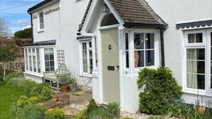A two-story white house with a small front garden, a door marked with the number 8, and a bench.