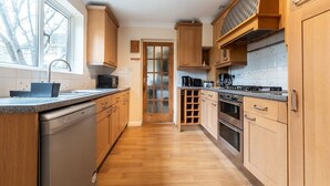 Una cocina con armarios de madera, lavavajillas, estufa y ventana que deja entrar luz natural.