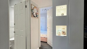 Un couloir doté d’un sol recouvert de moquette, d’une porte blanche et d’un luminaire fixé au mur.