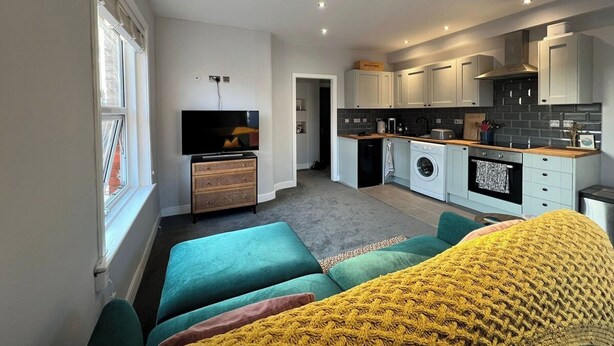Un appartement moderne comprenant un espace de vie, une cuisine et une buanderie.