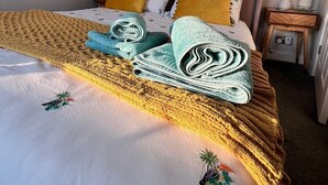 Un lit bien fait, avec une couvre-lit à motifs, des oreillers et une couverture pliée.