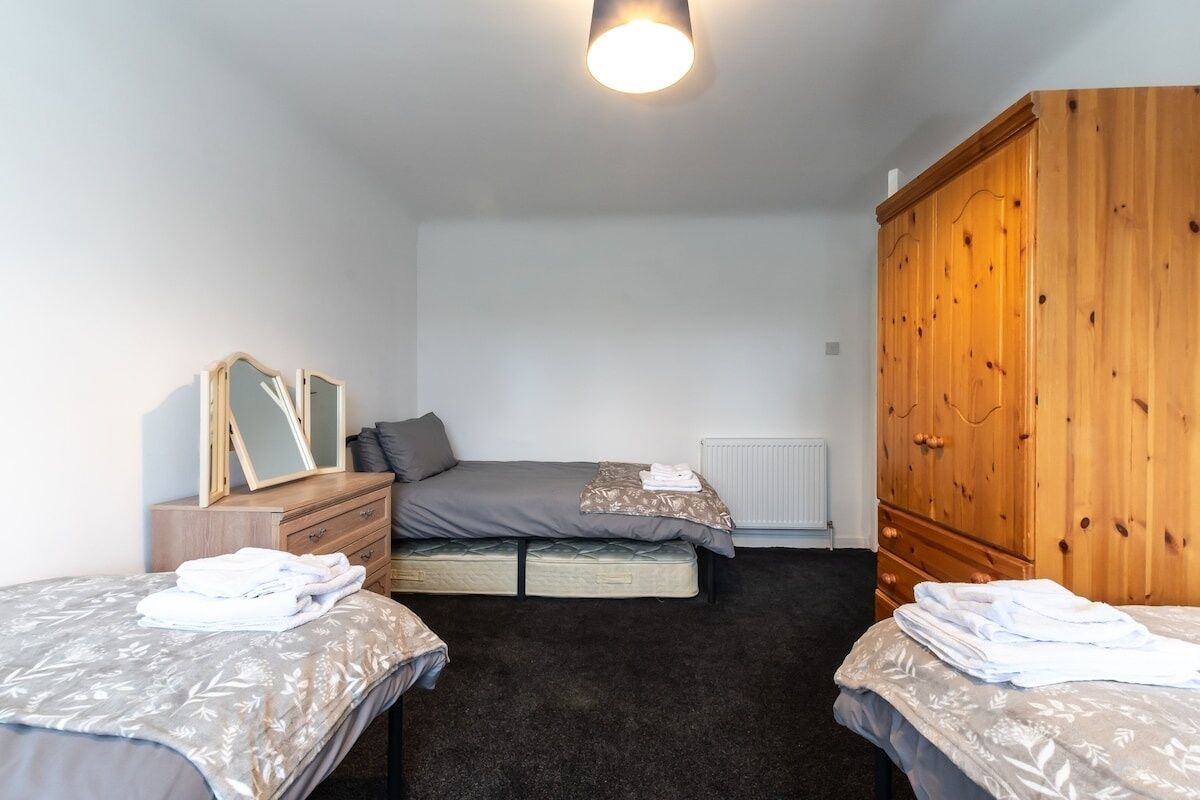 Une chambre à coucher avec un lit, une armoire, une commode et un miroir.