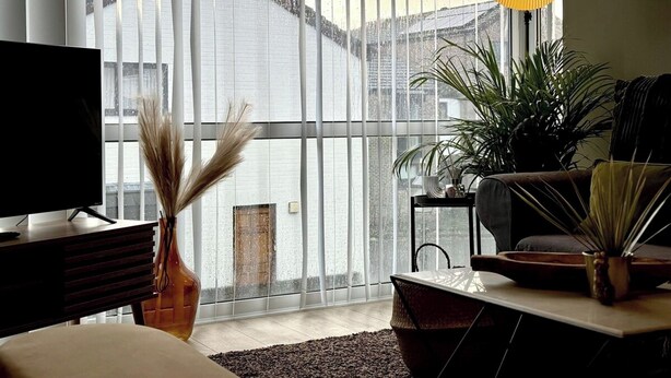 Un salon moderne doté d’une grande fenêtre, d’un téléviseur à écran plat, d’un canapé, d’une table basse et d’une lampe suspendue.