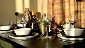 Une table à manger dressée avec des assiettes, des bols et des verres à vin, agrémentée de vases décoratifs et d’un chandelier.