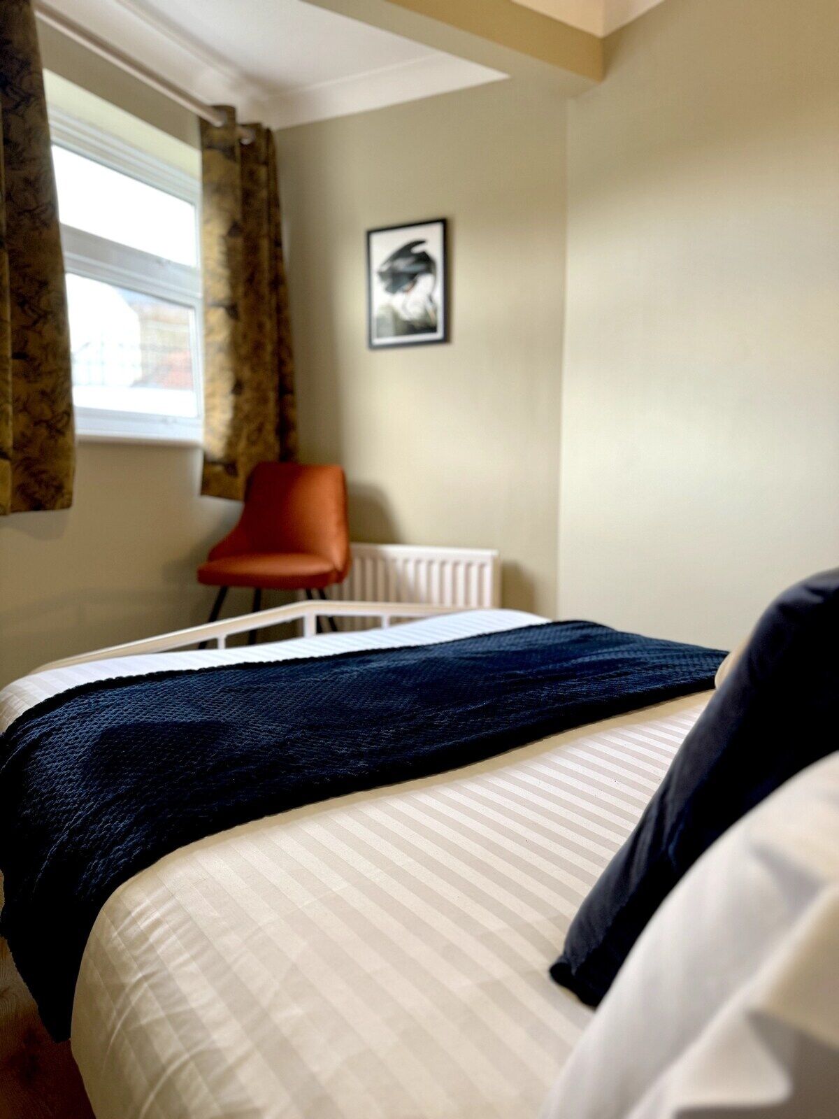 A hotel room with a bed, a chair, and a radiator.