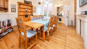 A dining area with a wooden table and chairs, a bookshelf, and a fireplace. - Charming Edwardian 5 Bed House | London (Elstree)