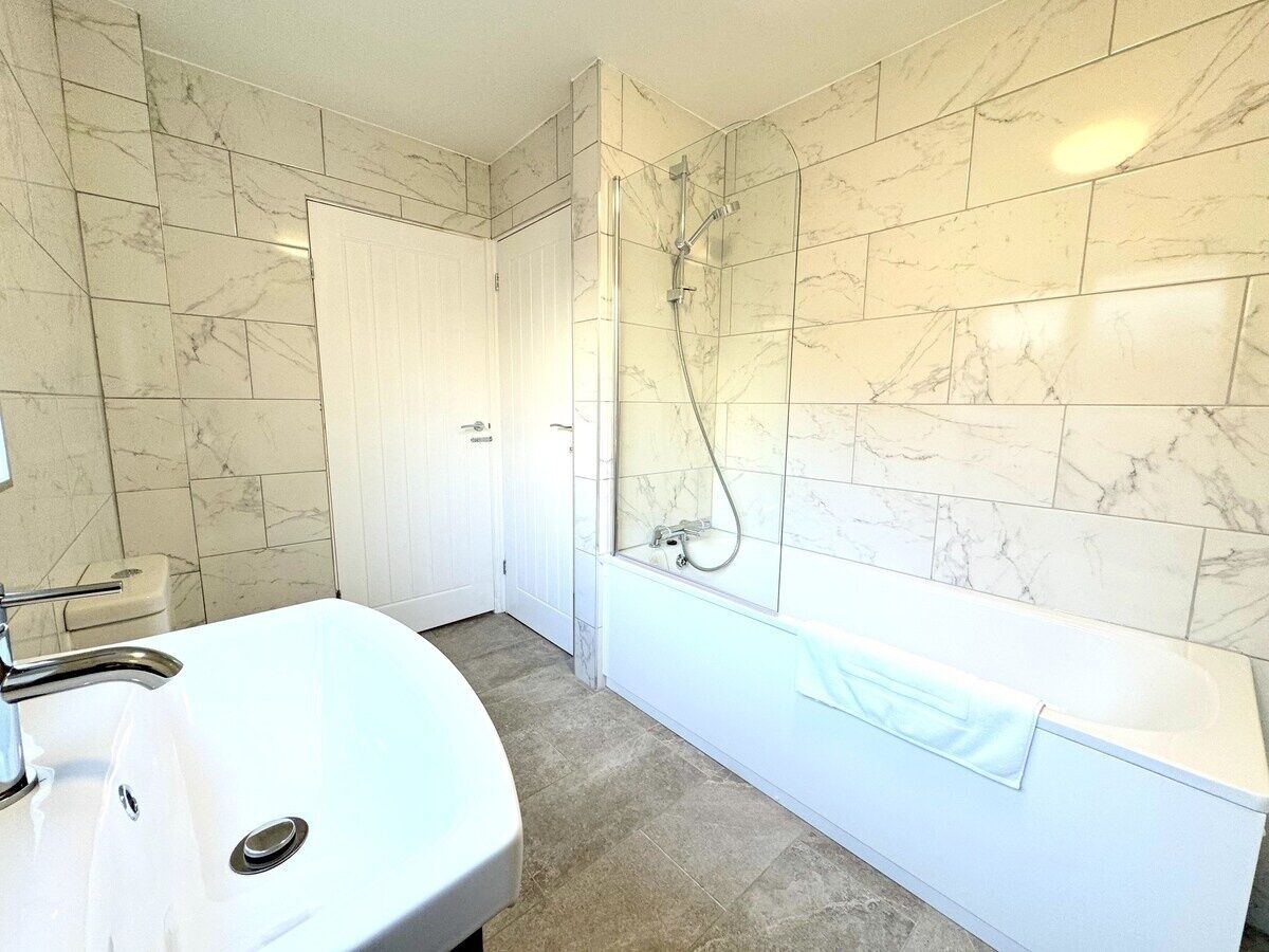 A bathroom with a white sink, a bathtub, and a shower.