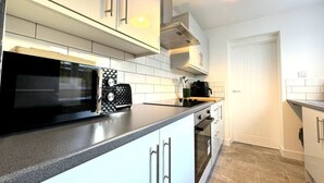 Una cocina moderna con armarios blancos, un microondas negro y un horno empotrado.