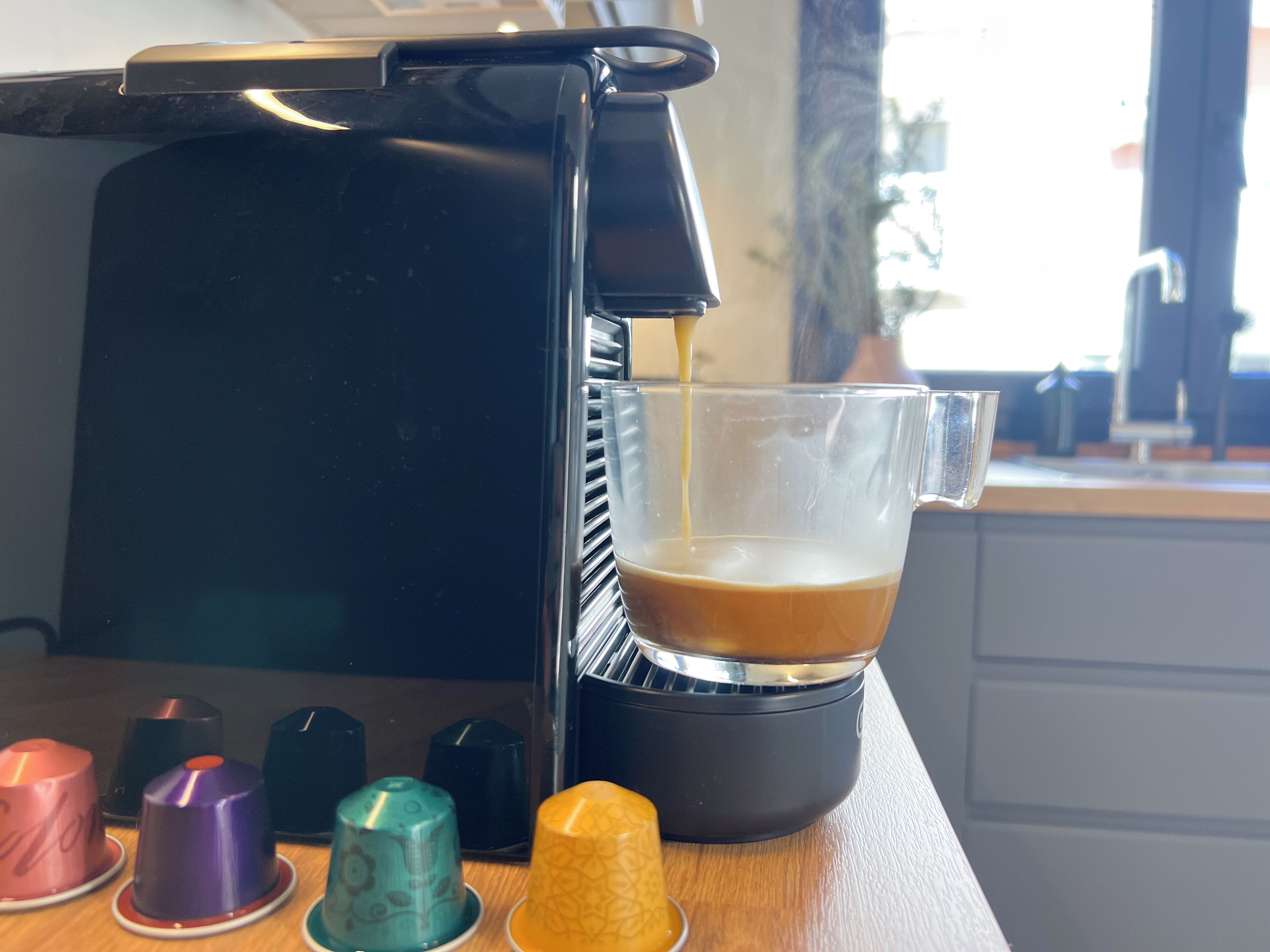 A coffee machine dispensing coffee into a glass cup.