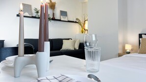 Un coin repas aménagé avec soin, comprenant une table blanche, de la vaisselle transparente et des bougies.