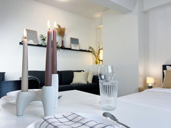 A neatly arranged dining area with a white table, clear glassware, and candles.