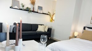 Une chambre d’hôtel moderne avec un lit, une table à manger décorée de bougies, un verre et un canapé.